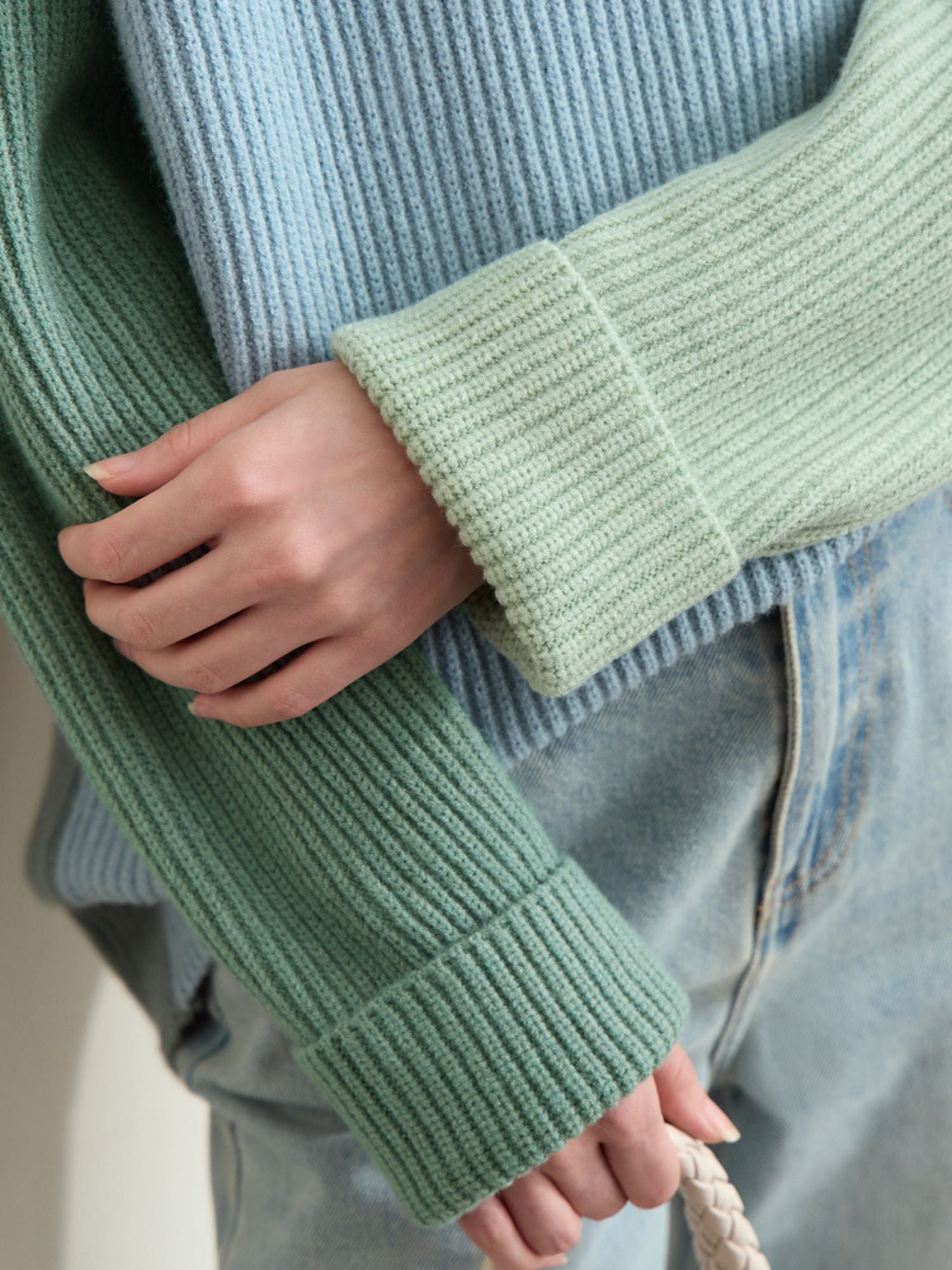 Close-up of hand touching mint sweater sleeve to show knit rib detail