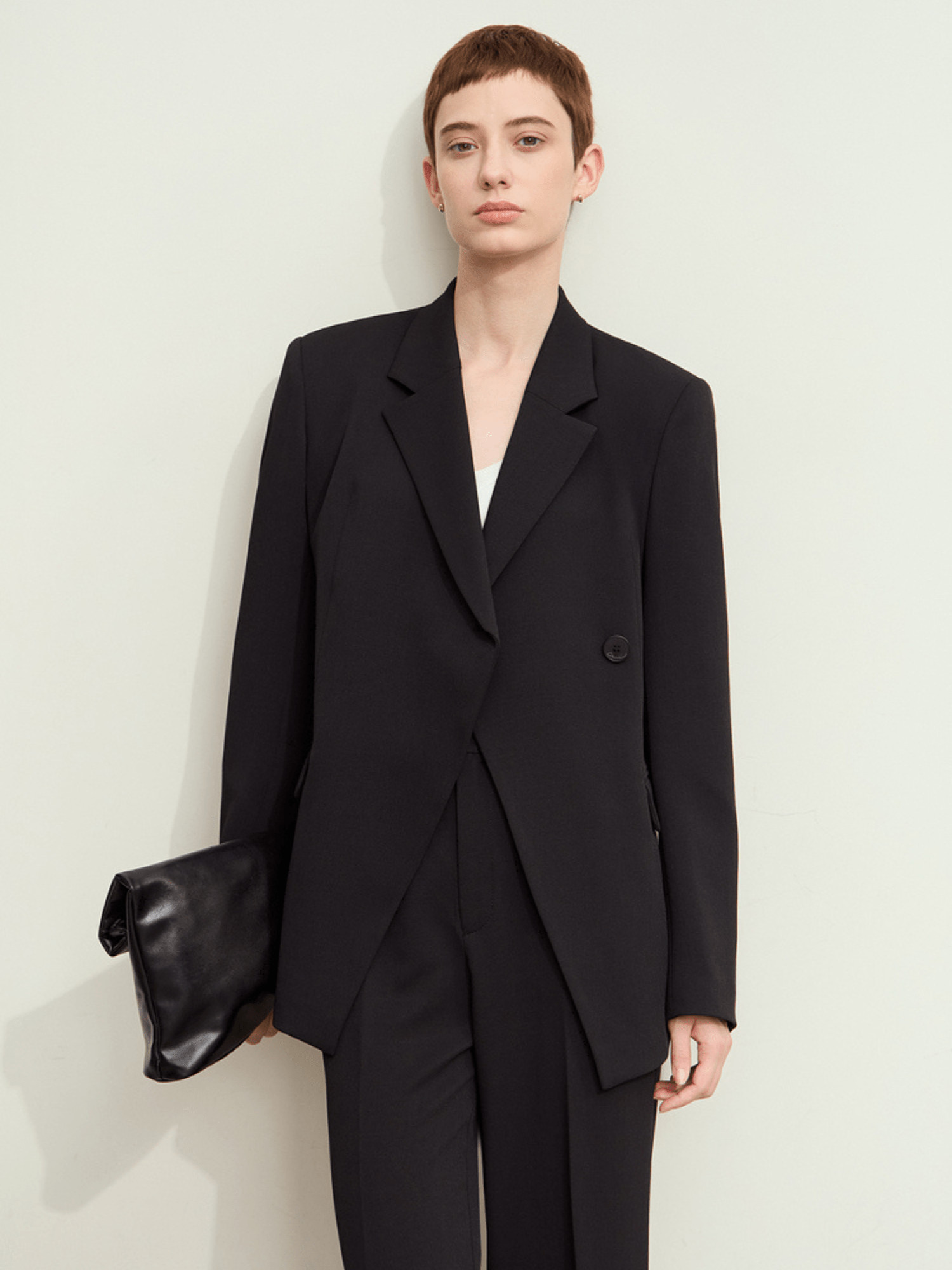 Model wearing black double‑breasted tailored blazer with notch lapels and matching trousers