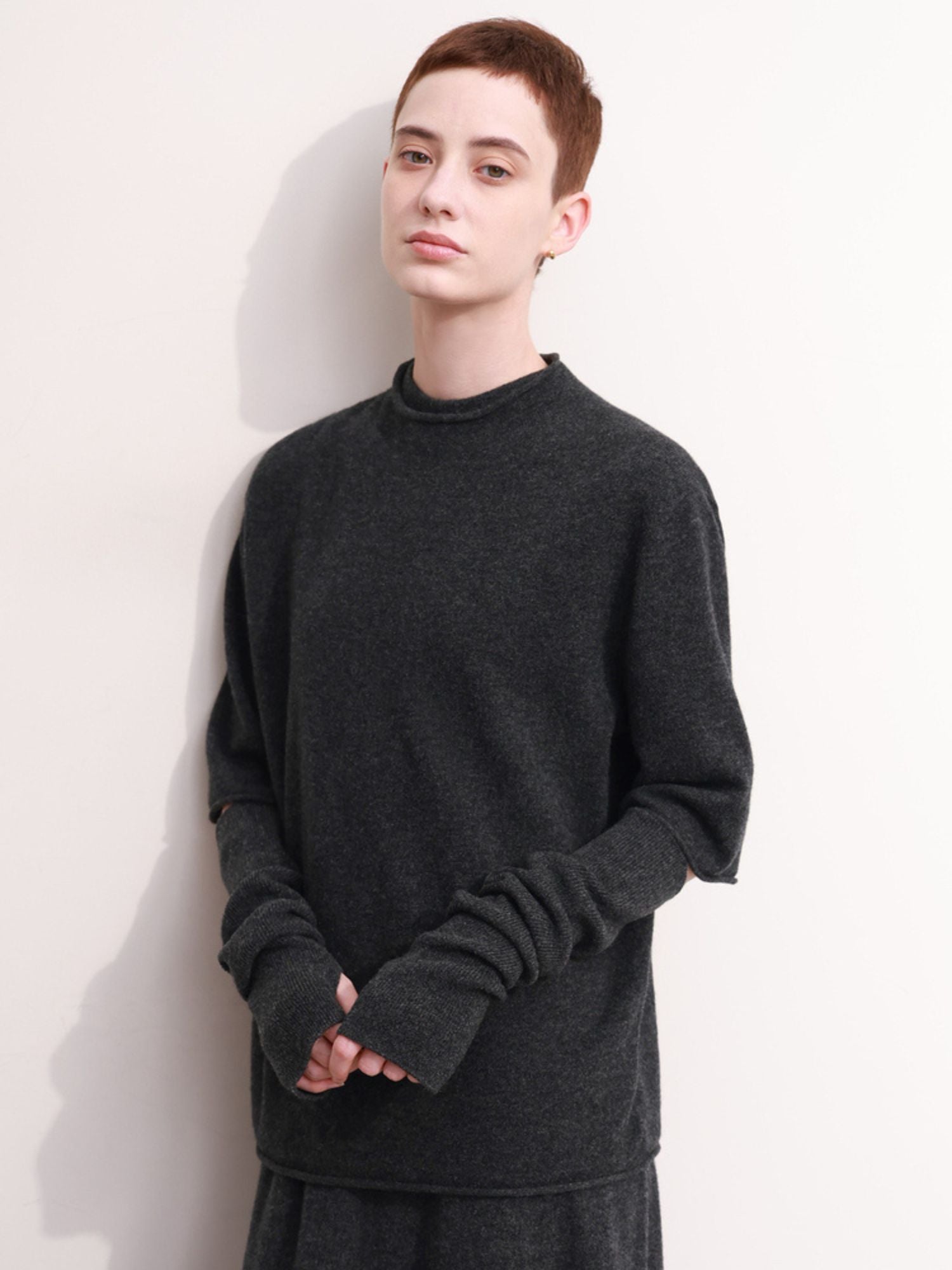 Model wearing oversized charcoal grey sweater with long slit sleeves paired with a matching skirt