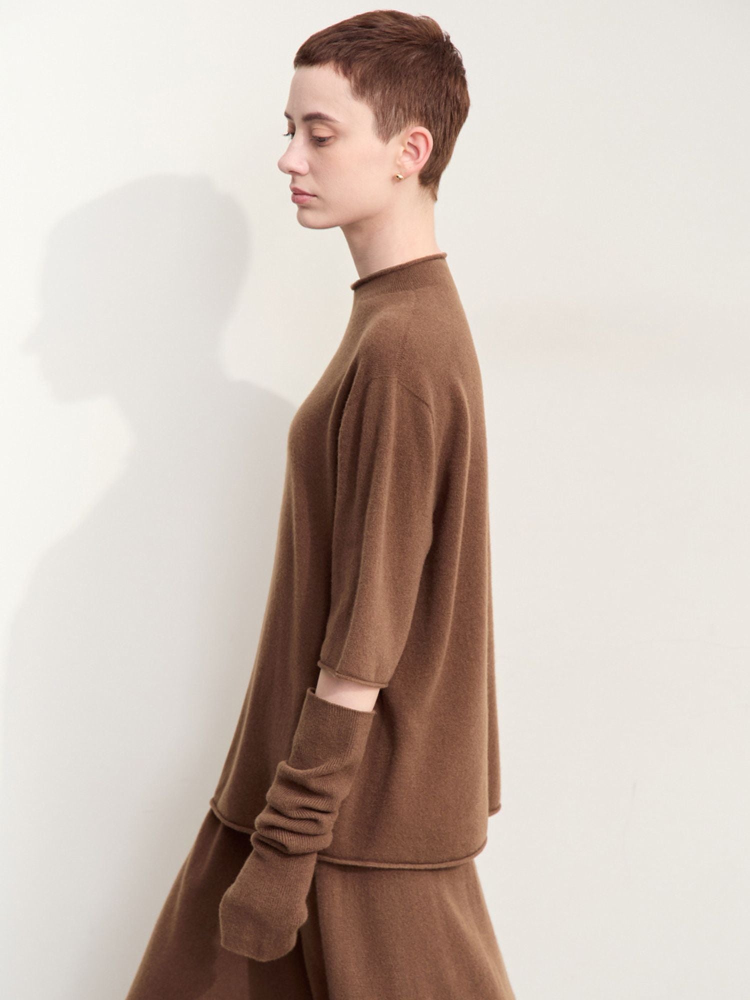 Side view of brown sweater displaying silhouette and sleeve slit detail