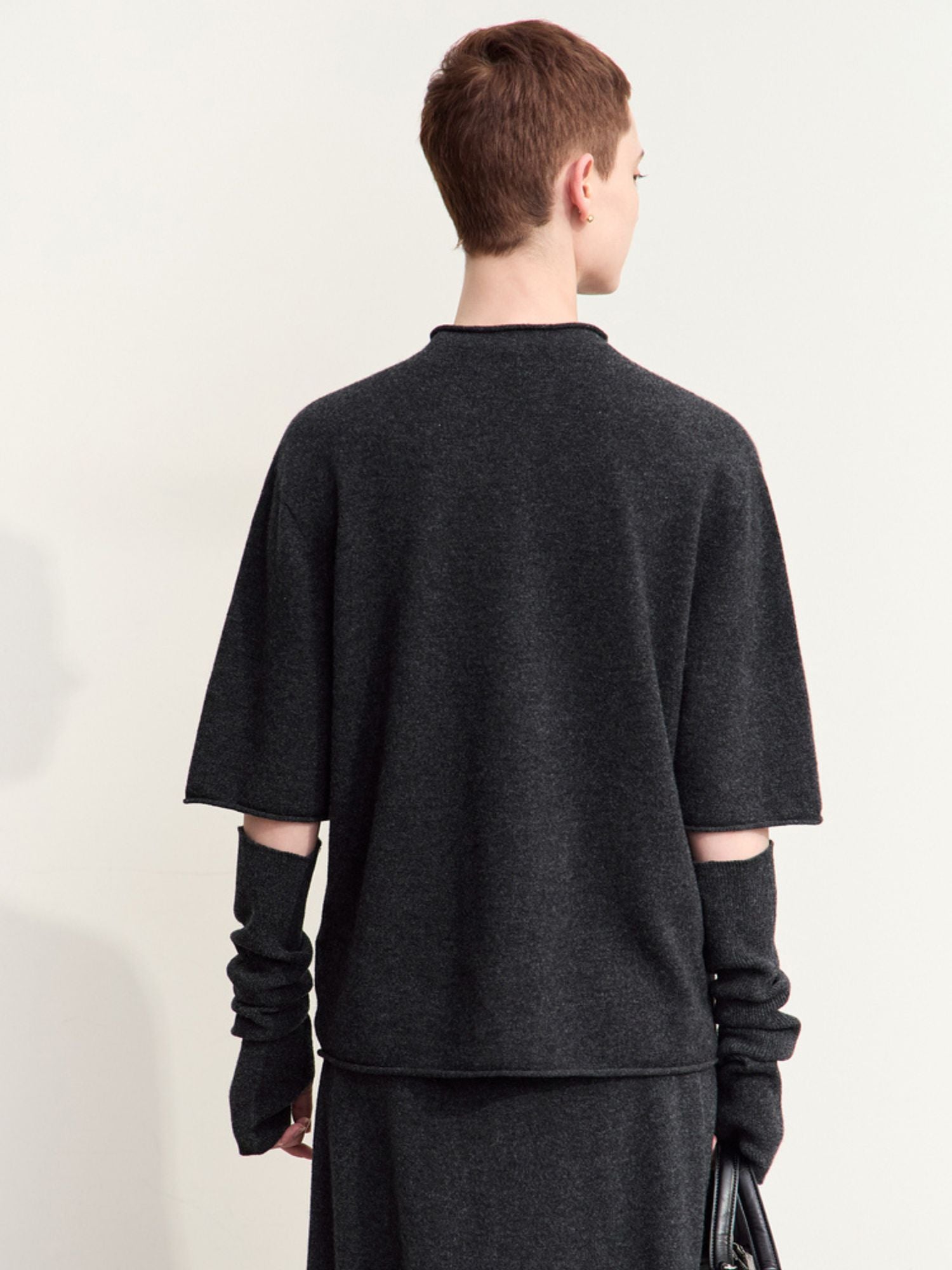 Back view of charcoal grey sweater showing relaxed drape and slit sleeves
