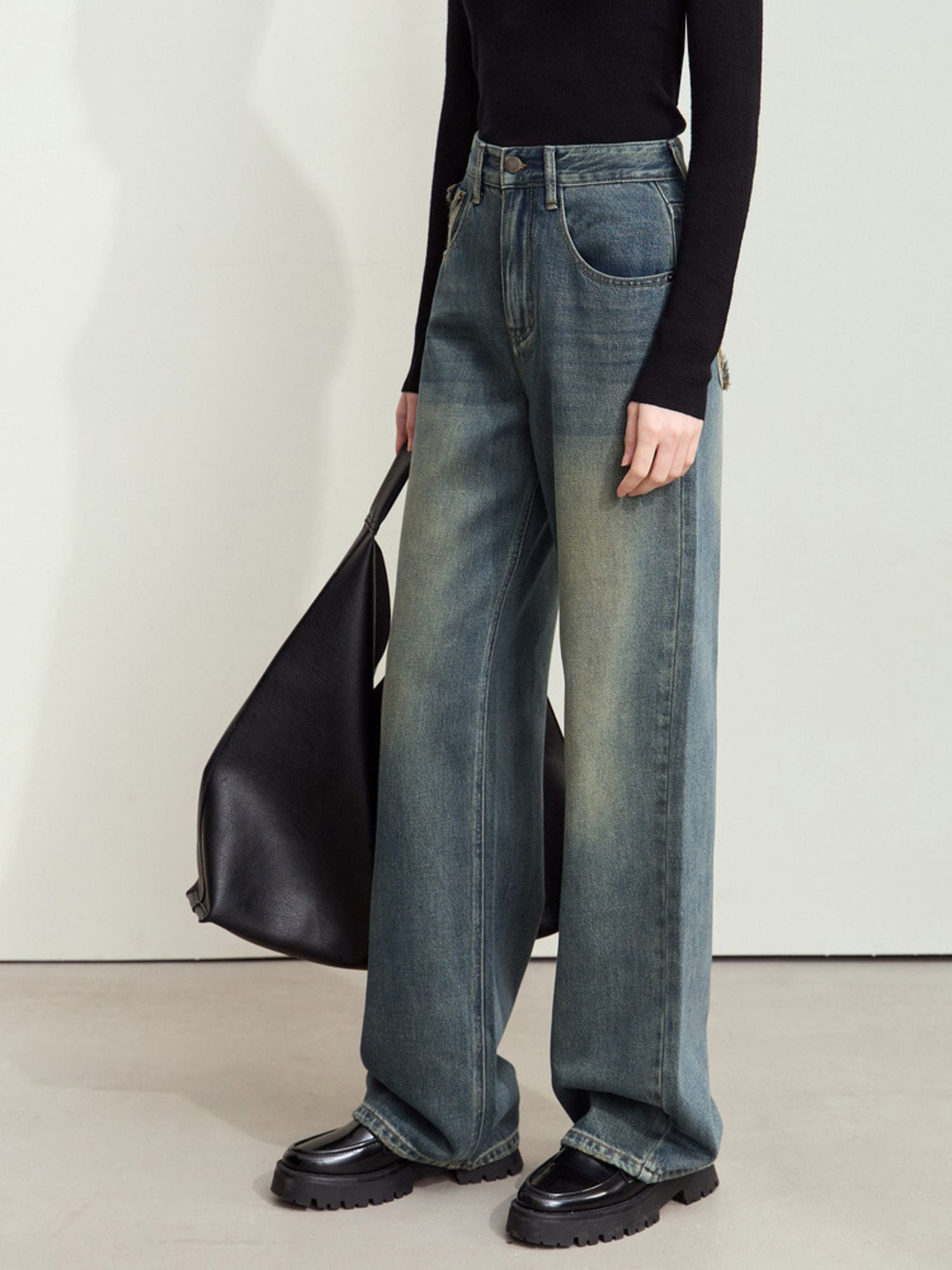 Three-quarter front view of jeans styled with a black top and black clutch, showcasing front pocket and waist fit