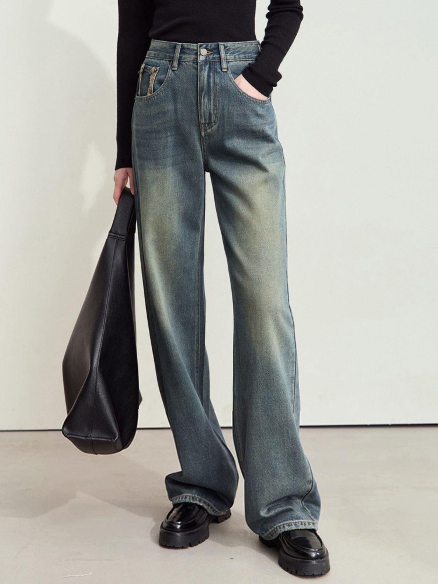 Three-quarter side view of faded wide-leg jeans with visible creasing and relaxed fit