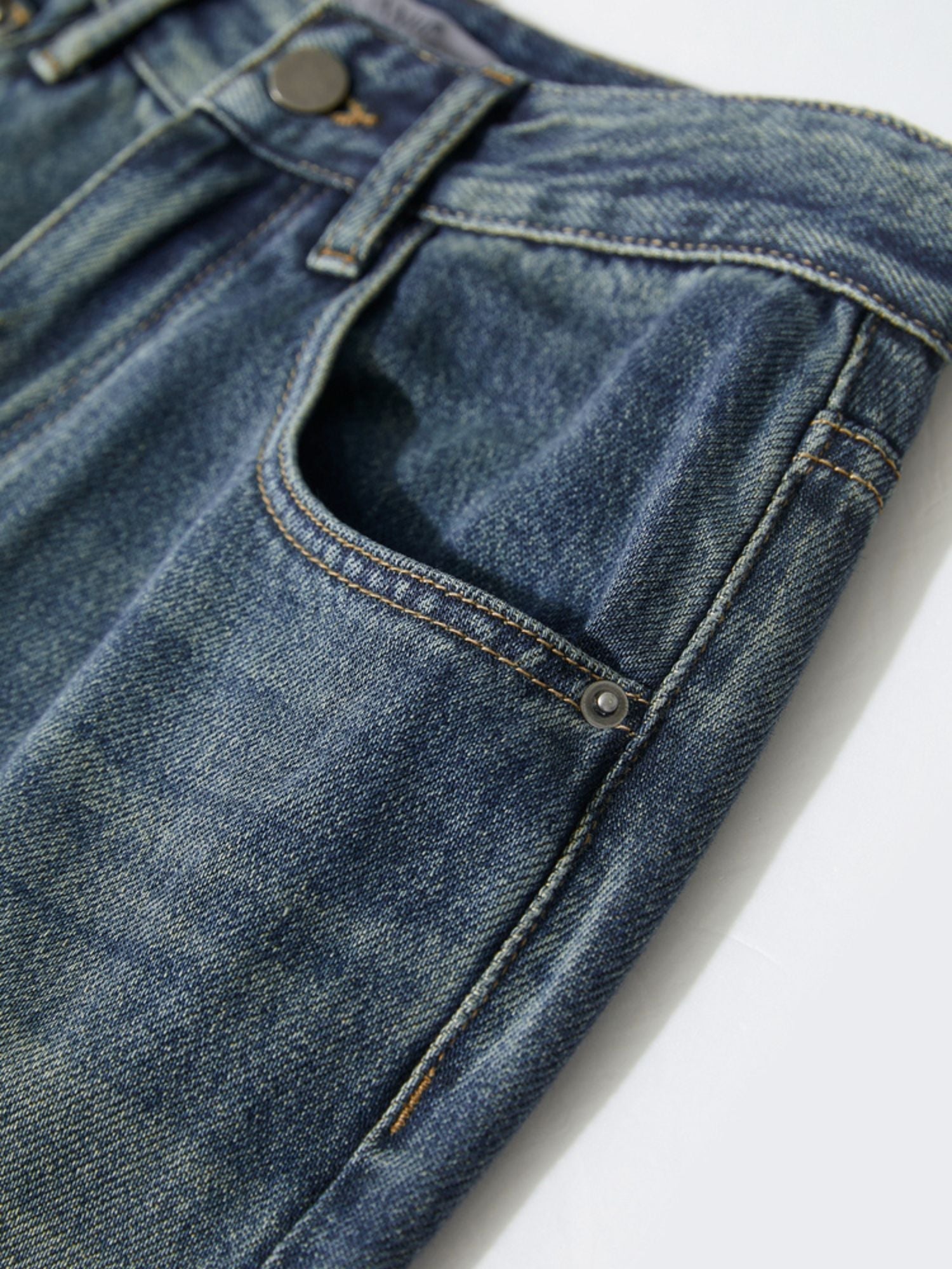 Flat-lay front view of blue jeans with noticeable thigh fading and worn-in texture