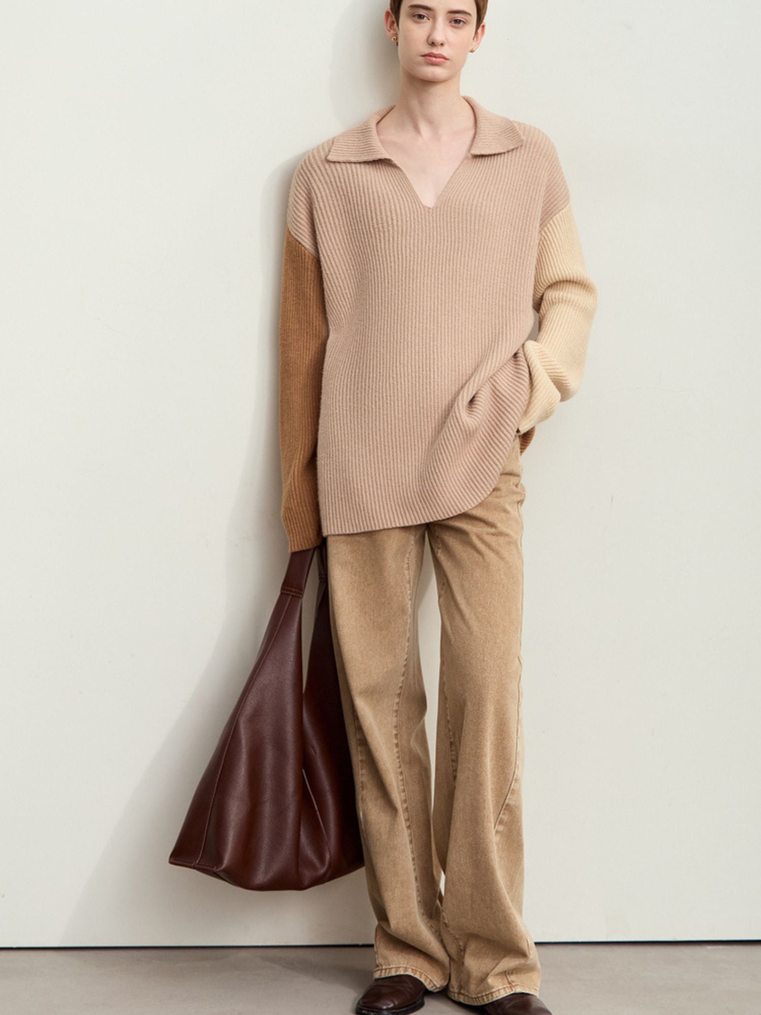 Three-quarter front view of tan wide-leg corduroy pants styled with a beige long-sleeve top and brown tote bag