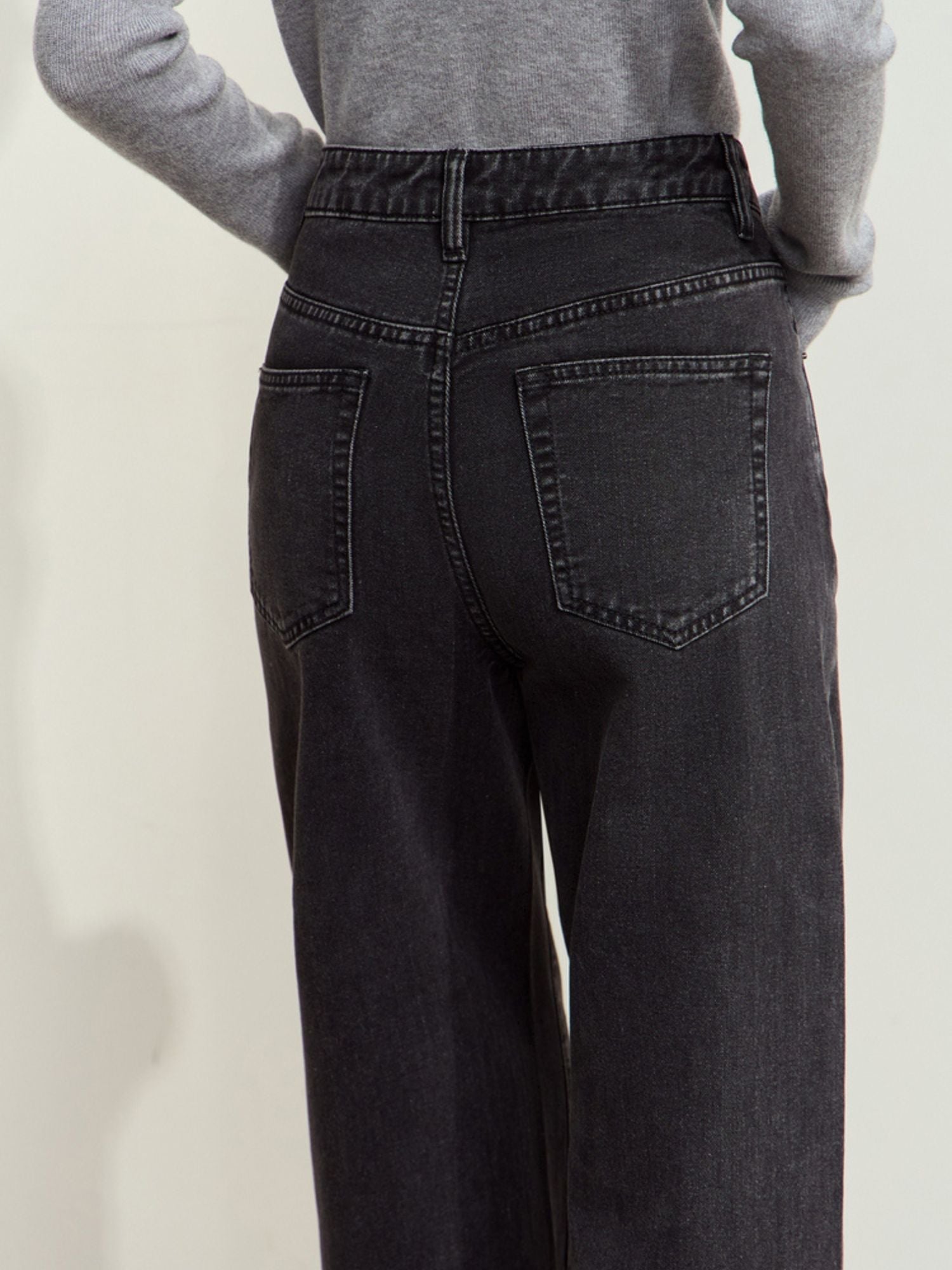 Back view of black corduroy pants, highlighting the seam and back pocket details