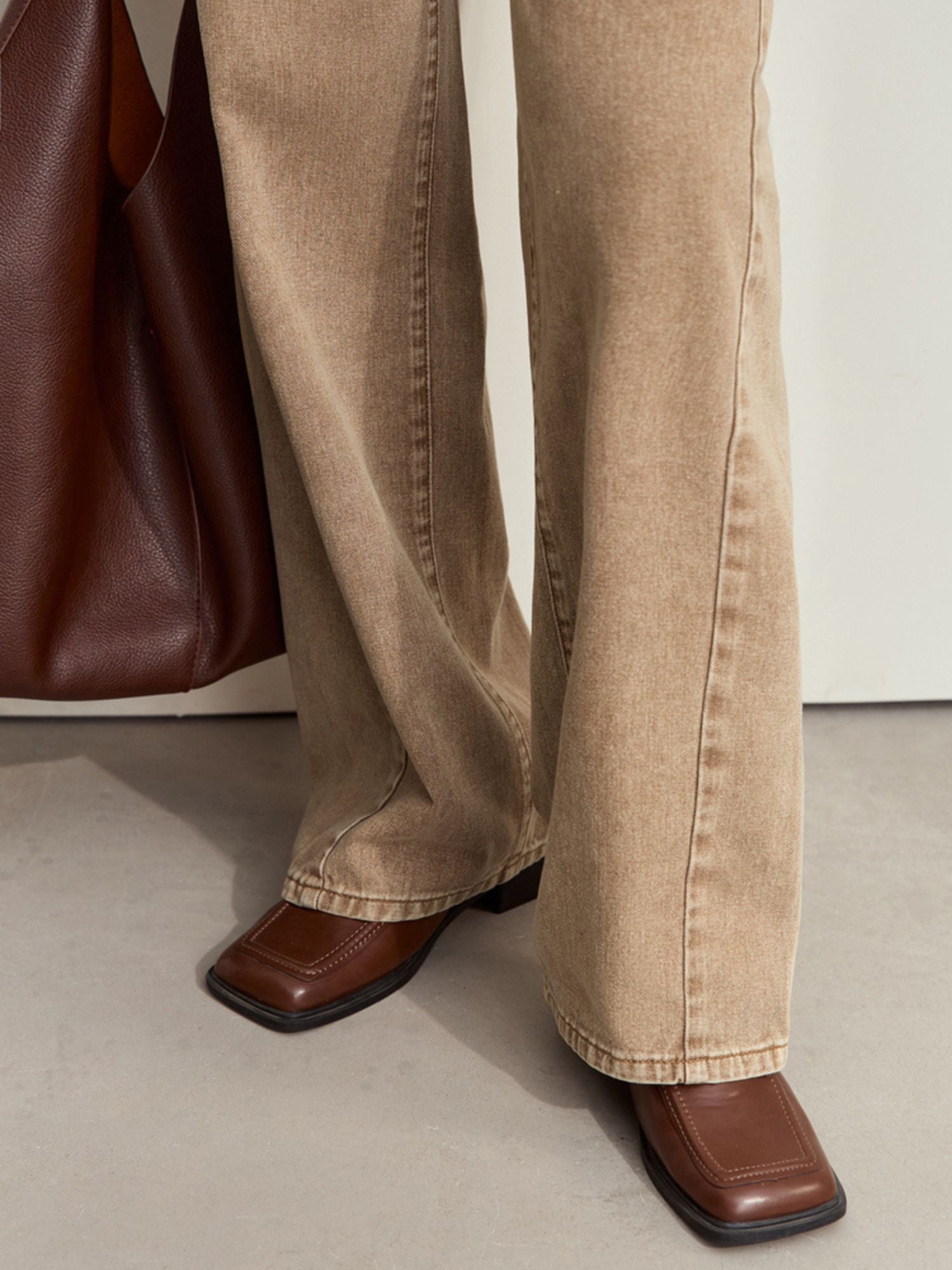 Lower front view of tan corduroy pants, styled with a brown bag and heeled shoes