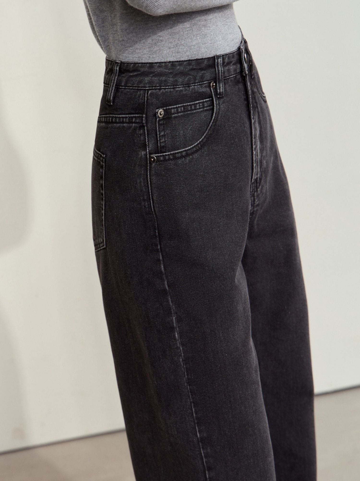 Three-quarter side view of black corduroy pants paired with a fitted grey top